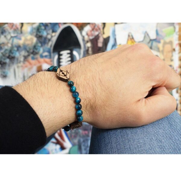 main portant un bracelet avec perles bleus et pendentifs en bois