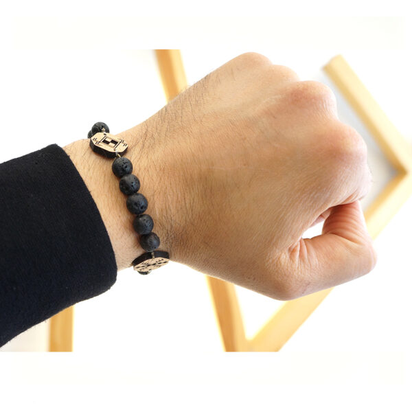 main portant un bracelet en pierre volcanique