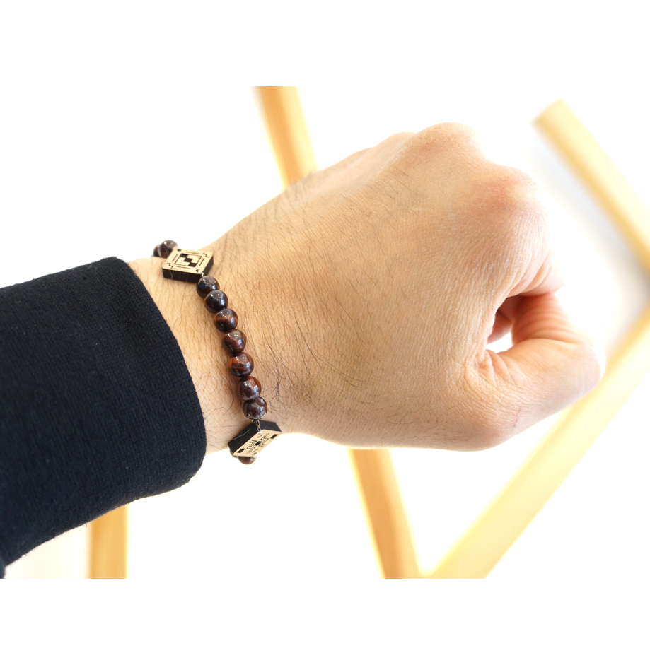 main portant un bracelet avec perles et pendentif en bois