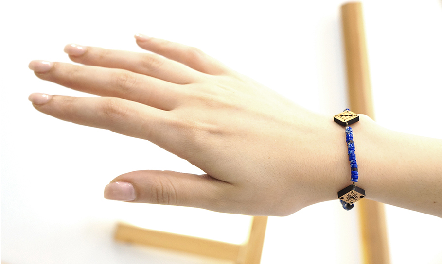 Main avec bracelet berbère bleu et pendentif en bois