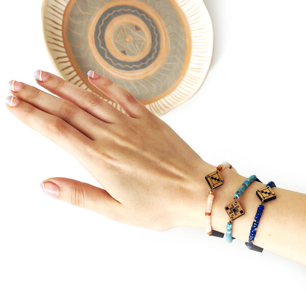Main qui porte 3 bracelets berbères en bois et en pierre naturelles