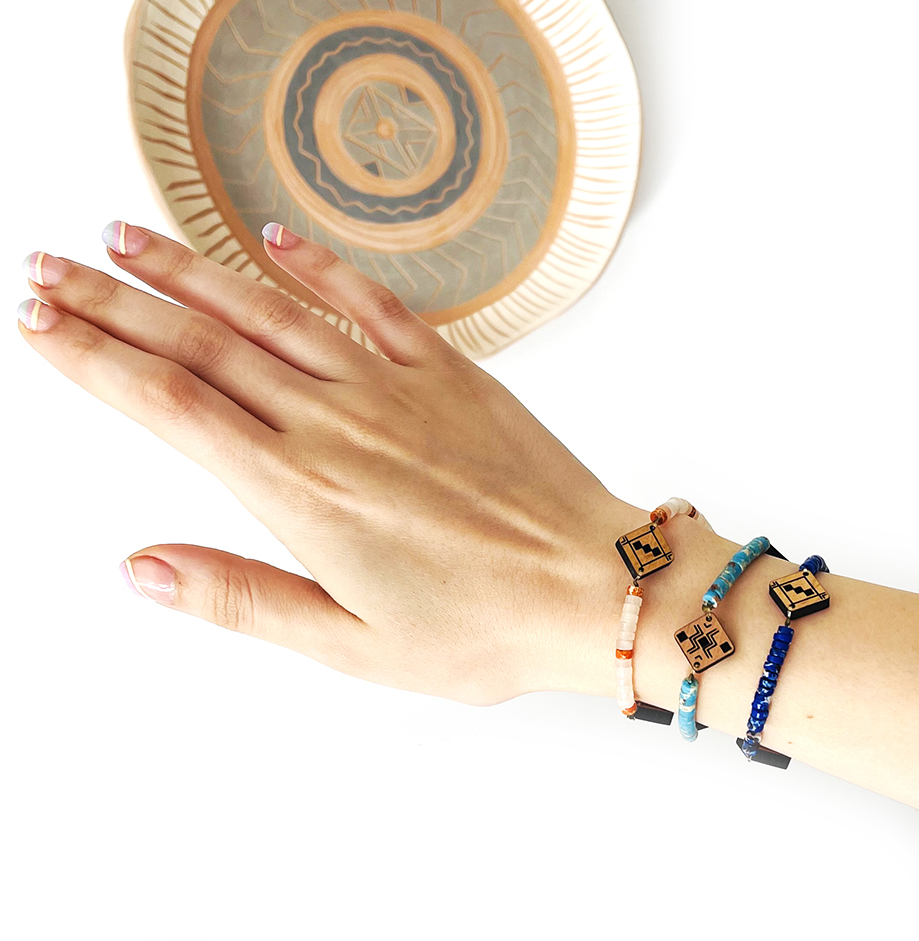 Main qui porte 3 bracelets berbères en bois et en pierre naturelles